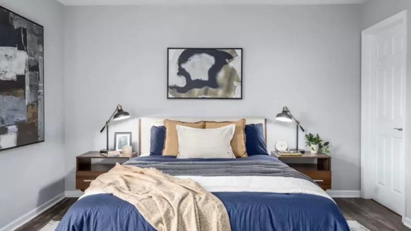 A bedroom with a neatly made bed and matching nightstands, decorated in warm neutral tones.