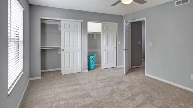 A spacious bedroom with two closets featuring sliding doors and soft carpeting.