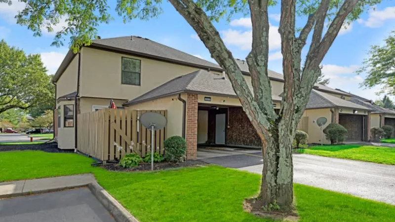 The exterior view of a townhome with a private fenced patio area and lush green grass.