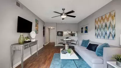 A stylish open-concept living and dining area with teal accents and contemporary decor.