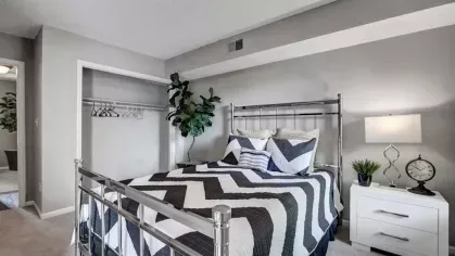 A modern bedroom featuring a geometric-patterned bedspread, a bedside table, and wall decor.