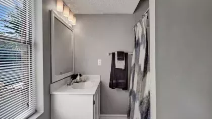 A bathroom with a white vanity, modern lighting, and a window allowing natural light.