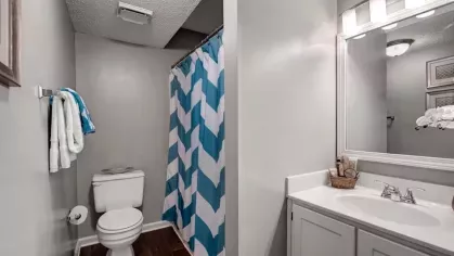 A bathroom featuring a white vanity, a toilet, and a blue and white chevron shower curtain.