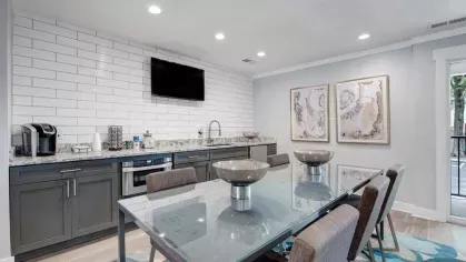 A communal kitchen and dining space featuring a long table, a coffee station, and contemporary decor.