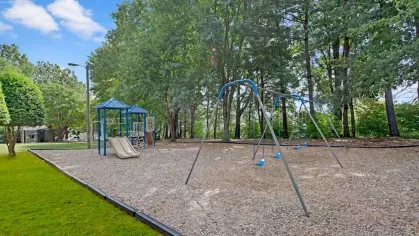 A swing set and playground area shaded by trees, perfect for outdoor fun.