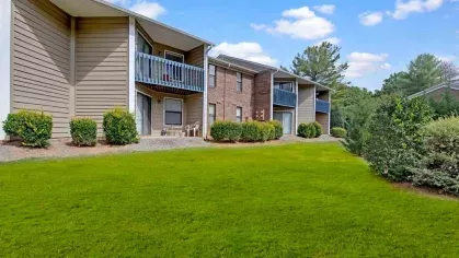 A side view of apartment units with balconies surrounded by well-maintained grass.