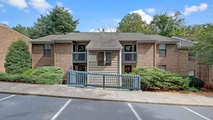 An apartment complex building featuring a parking lot in the foreground.