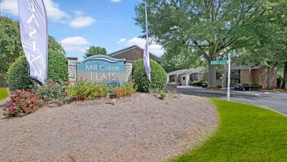The Mill Creek Flats signage surrounded by vibrant landscaping at the entrance of the complex.