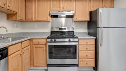 A well-equipped modern kitchen featuring wooden cabinets, a stainless steel stove, and a refrigerator.