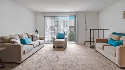 A bright and spacious living room with large windows and comfortable beige sofas.