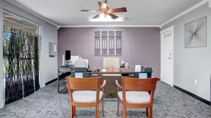 The leasing office featuring a central desk, chairs, and tasteful wall art.