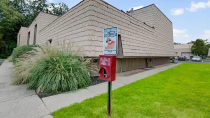 A dog waste station surrounded by lush green grass and landscaping.