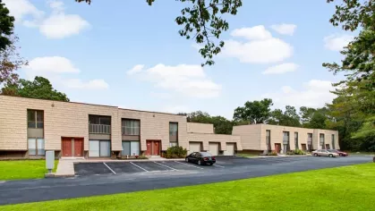 A view of the apartment buildings with beige exteriors and a parking lot in front.