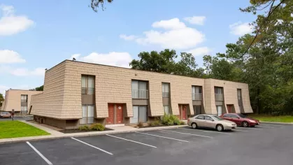A closer perspective of the apartments with red doors and a neatly arranged parking area.