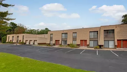 a row of well-maintained apartment buildings with parking spaces and green landscaping.