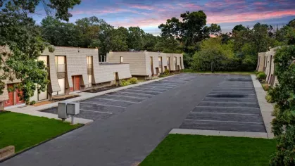 the apartments at dusk, with warm lighting accentuating the buildings and an empty, clean parking lot.