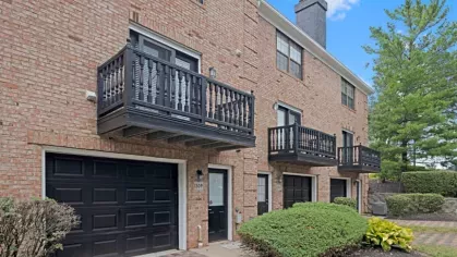 Exterior of Parkhill townhome-style apartments displaying black balconies, garages, and brick construction with well-manicured greenery.