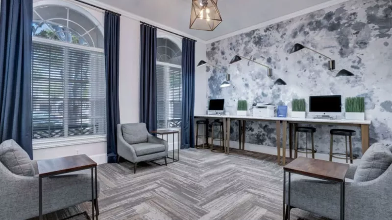 Stylish workspace with comfortable seating, computer stations, and a bold blue and white mural wall.