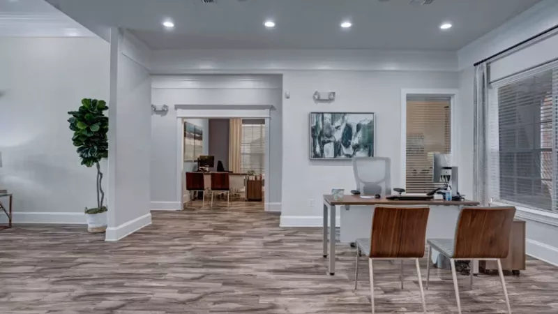 Open office space with wooden chairs, a desk, and modern artwork, creating a professional atmosphere.