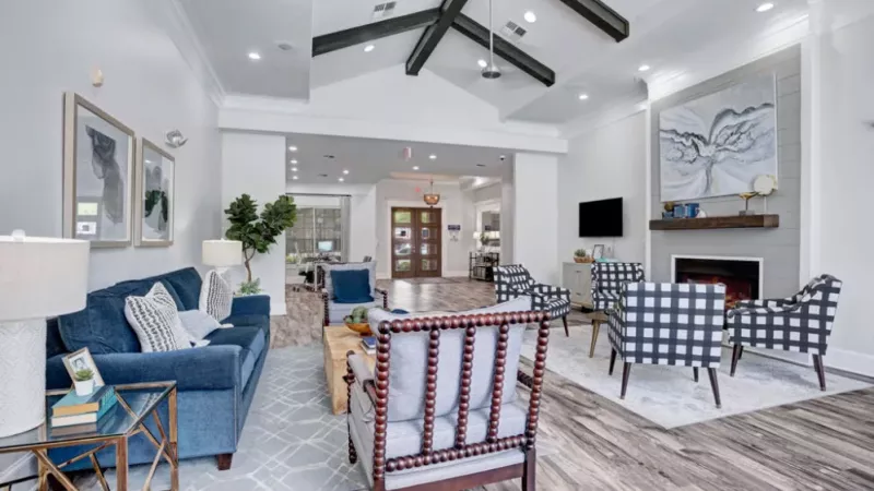 Inviting clubhouse with cozy seating, a fireplace, and contemporary decor under high vaulted ceilings.