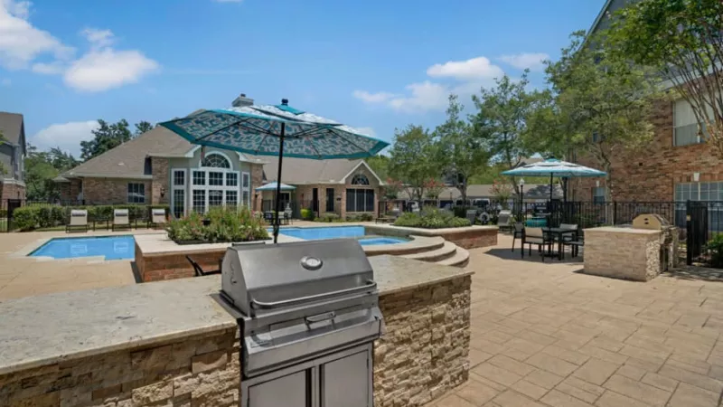 Outdoor grilling station with adjacent seating areas and a view of the pool.