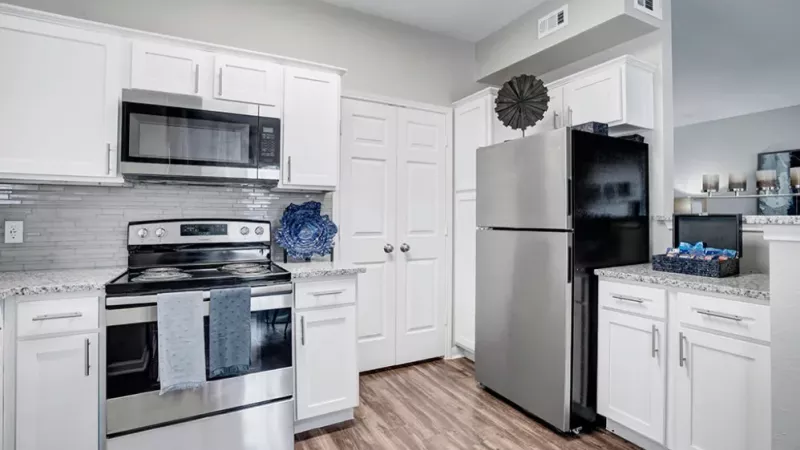 Another angle of the kitchen showing a stainless steel refrigerator and a cozy dining area in the background.