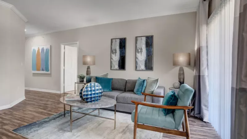 A chic living room with wood floors, elegant furniture, and contemporary artwork on the walls.