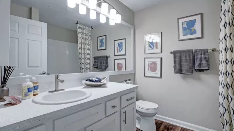 A modern bathroom with a large mirror, bright lighting, and white cabinetry for a clean, polished look.