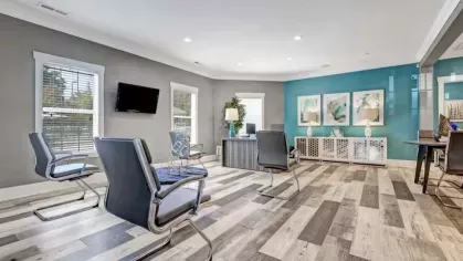 Sleek resident lounge with contemporary furnishings, wood-patterned flooring, wall art, and large windows.
