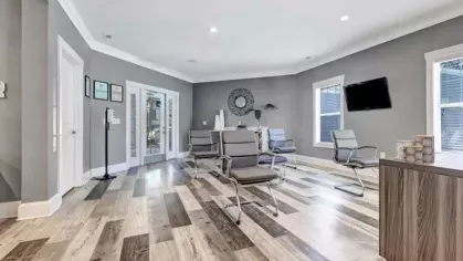 Bright resident lounge with stylish chairs, a mounted TV, and a feature wall with artwork and decorative accents.