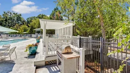 A shaded grilling station and poolside seating create the perfect outdoor entertainment space.