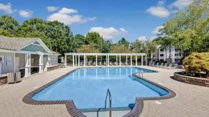 A second sparkling pool is set against a backdrop of lush landscaping and white pergolas.