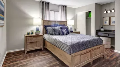 A cozy bedroom with a wooden bed frame, soft bedding, and built-in closet space, showcasing modern decor.