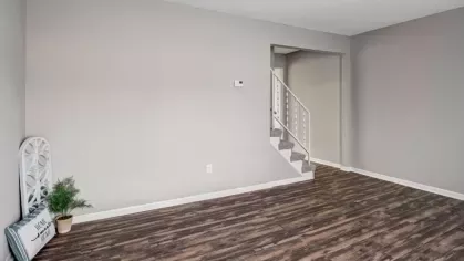 A bright living space with hardwood-style floors and a staircase, ready for personalized furnishing and decor.