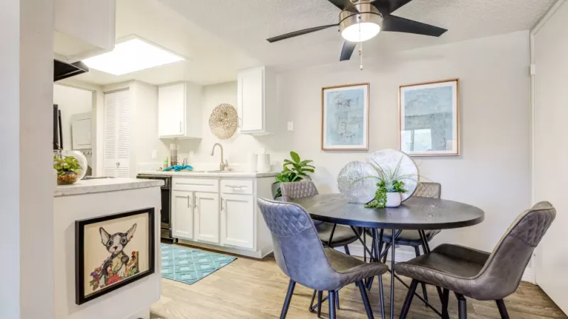 A dining area featuring a round table, contemporary chairs, and wall art near the open-concept kitchen.