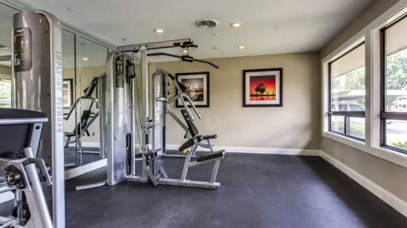A spacious workout area with weight machines and mirrors creating a bright, open environment.