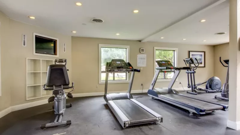 A fitness center with treadmills, elliptical machines, and a stationary bike in a clean, modern setting.
