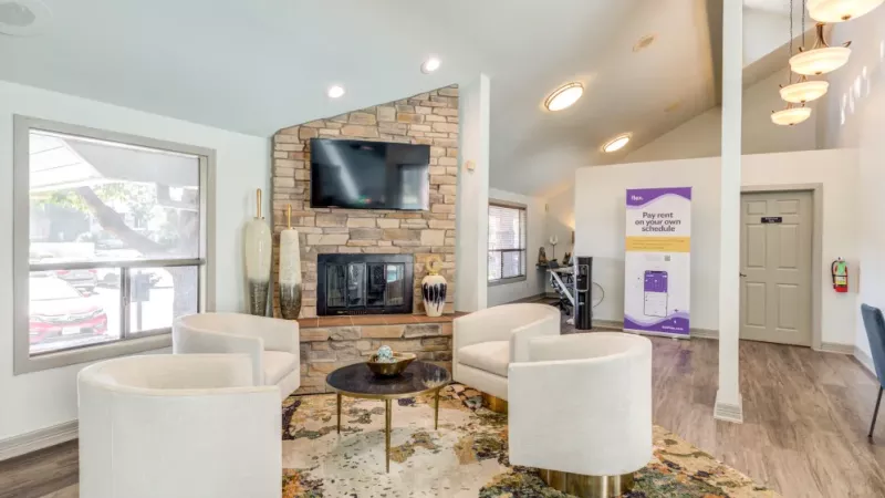 A cozy clubhouse area with a stone fireplace, flat-screen TV, and stylish seating for residents.