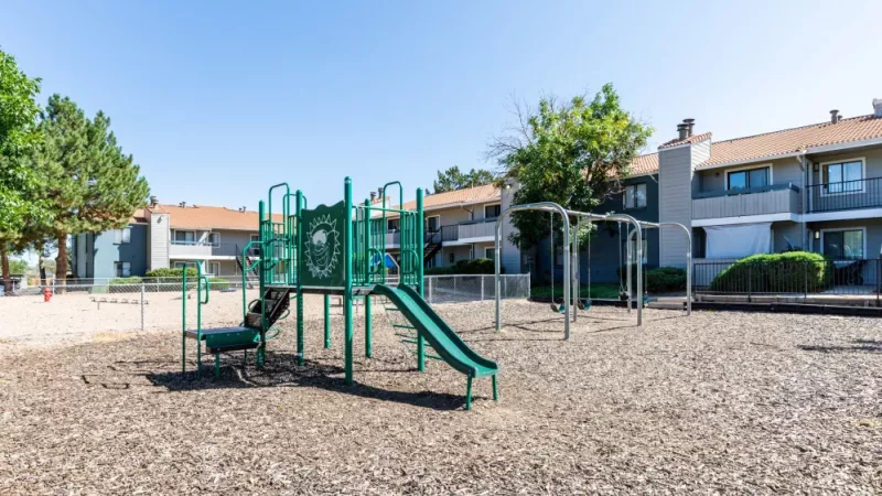 A children's playground with slides and swings located within an apartment community.