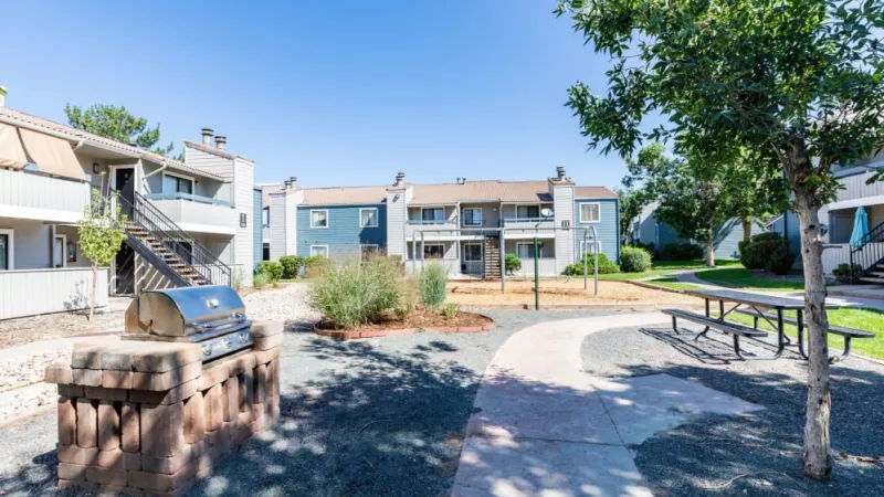 A community picnic area with a barbecue grill, picnic tables, and a landscaped path.