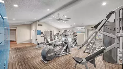 A fully equipped gym featuring advanced weight and cardio equipment under recessed lighting.