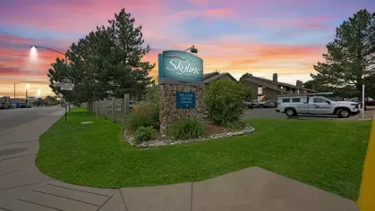A community welcome sign for Skyline Apartments with a colorful sunset in the background.