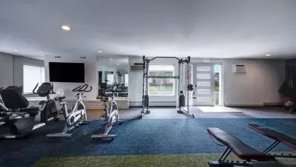 A gym with cardio machines, including treadmills and ellipticals, set in a clean and well-lit space.
