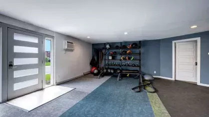 A fitness area with weight racks, exercise balls, and resistance equipment against a blue-accented wall.