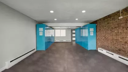 A spacious mailroom features bright blue parcel lockers against a brick and white wall design.
