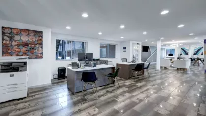 An open and modern leasing office features sleek workstations, printers, and stylish decor.