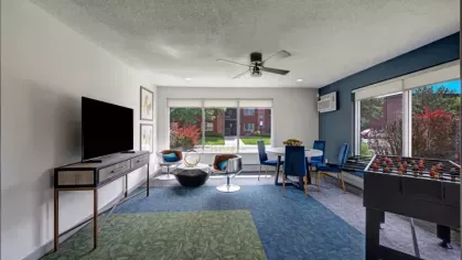 A vibrant resident lounge with a foosball table, seating area, and large windows for natural light.
