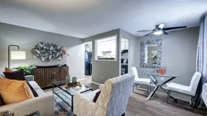 A bright kitchen space featuring a black refrigerator, marble countertops, and a stainless steel sink under decorative framed art.