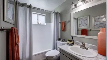 A well-lit bedroom with grey curtains, a carpeted floor, and an open closet door.