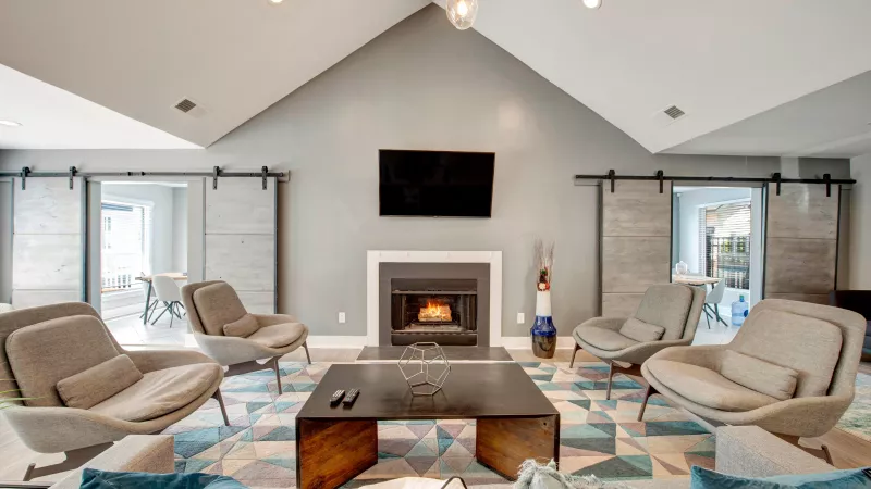 A sleek, modern lounge area with cozy seating, a large fireplace, and sliding barn doors adding charm.